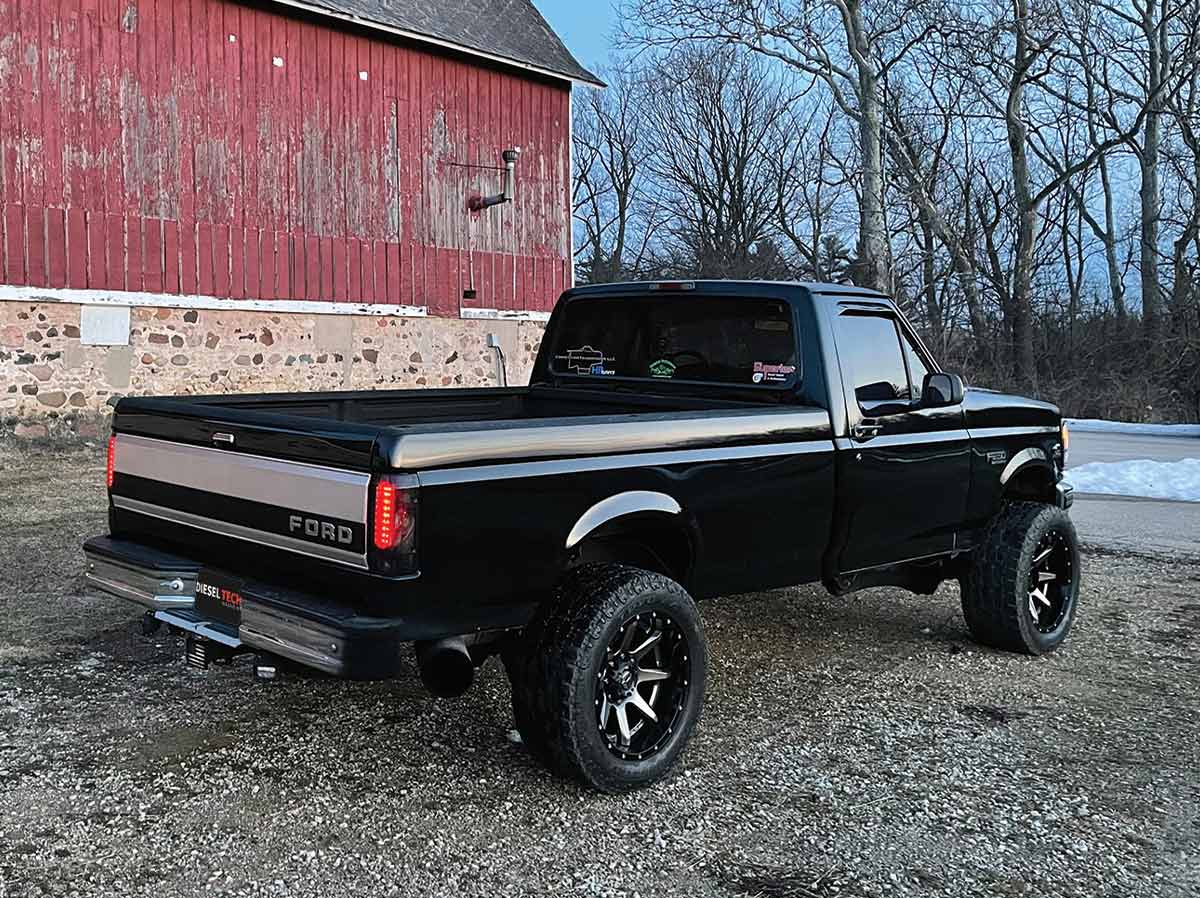 1996 Ford F250 parked next to a red barn, back tailgate view