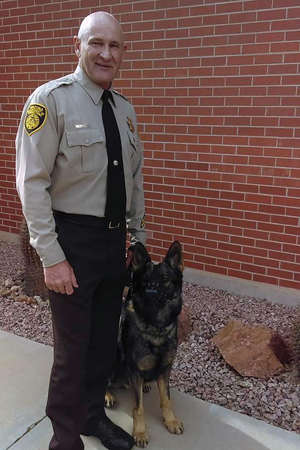 officer with canine by brick building