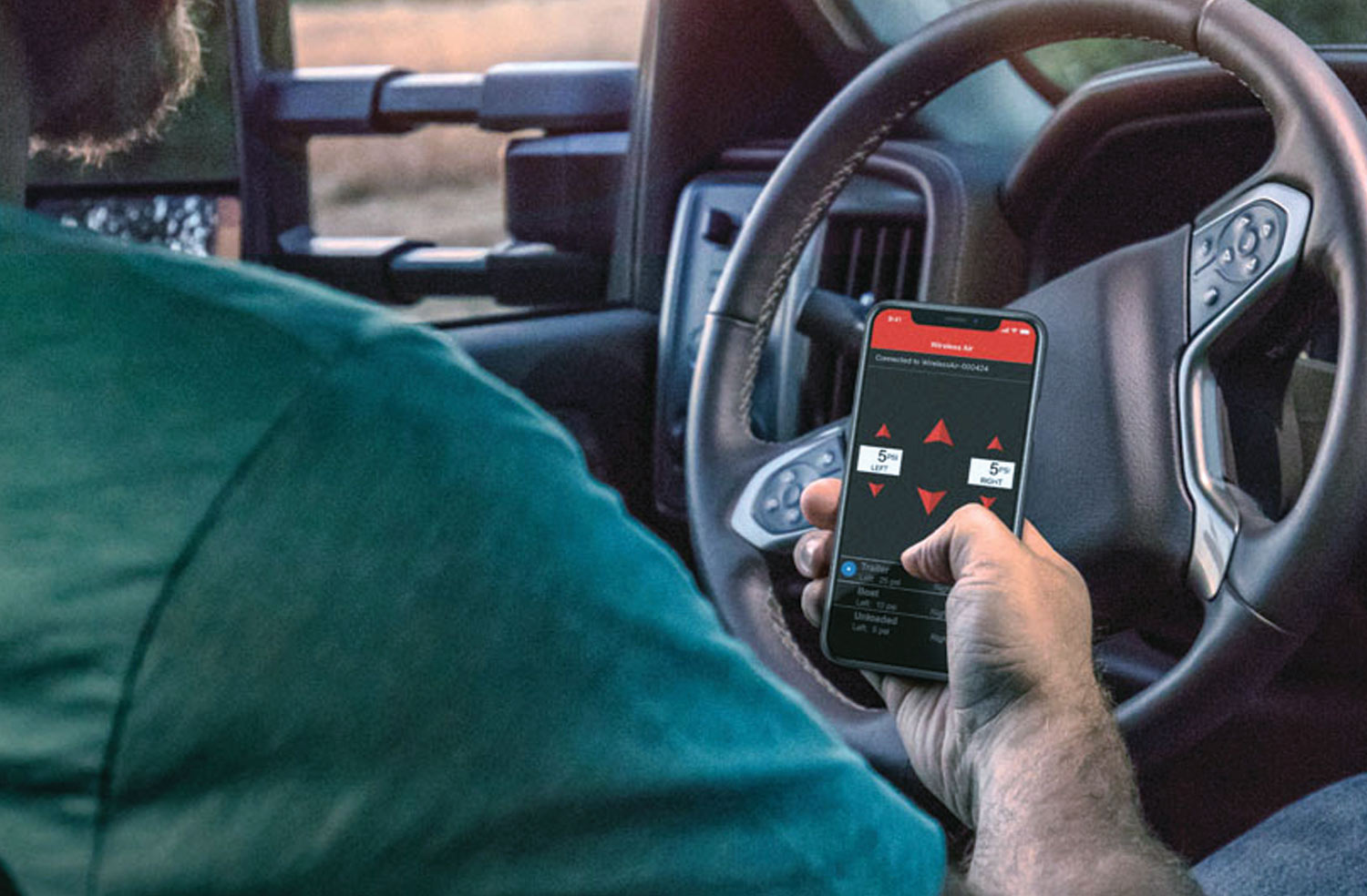 a man in a vehicle holds a smartphone with the WirelessAIR with EZ Mount System app open