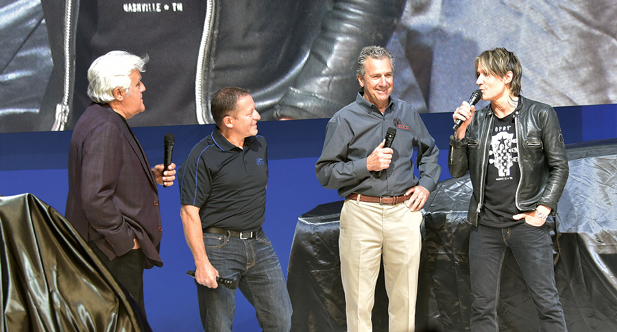Keith Urban on stage with other men at a car show