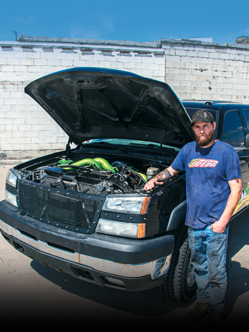 man standing next to his truck with the hood open