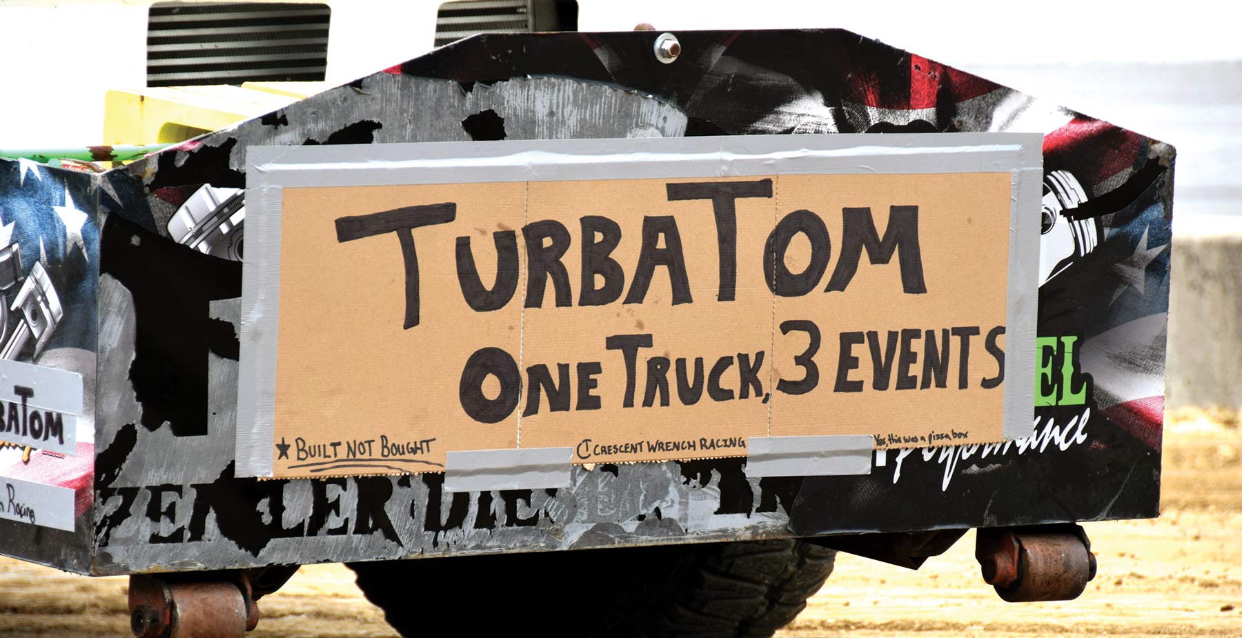 taped cardboard sign that says "TurbaTom: One Truck, 3 Events"