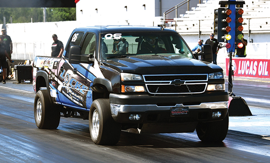 black truck with blue decals in a drag race