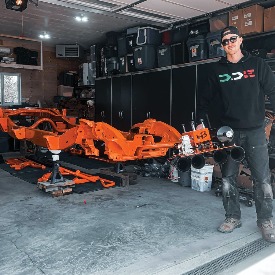 man standing in garage with orange truck frame