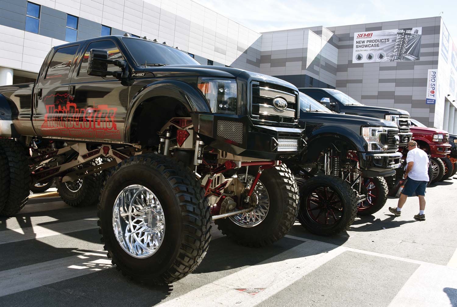 row of black lifted trucks at an event