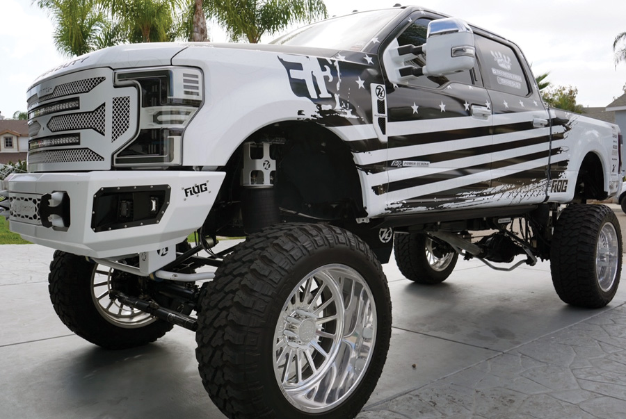 lifted white truck with a black American flag design on the side